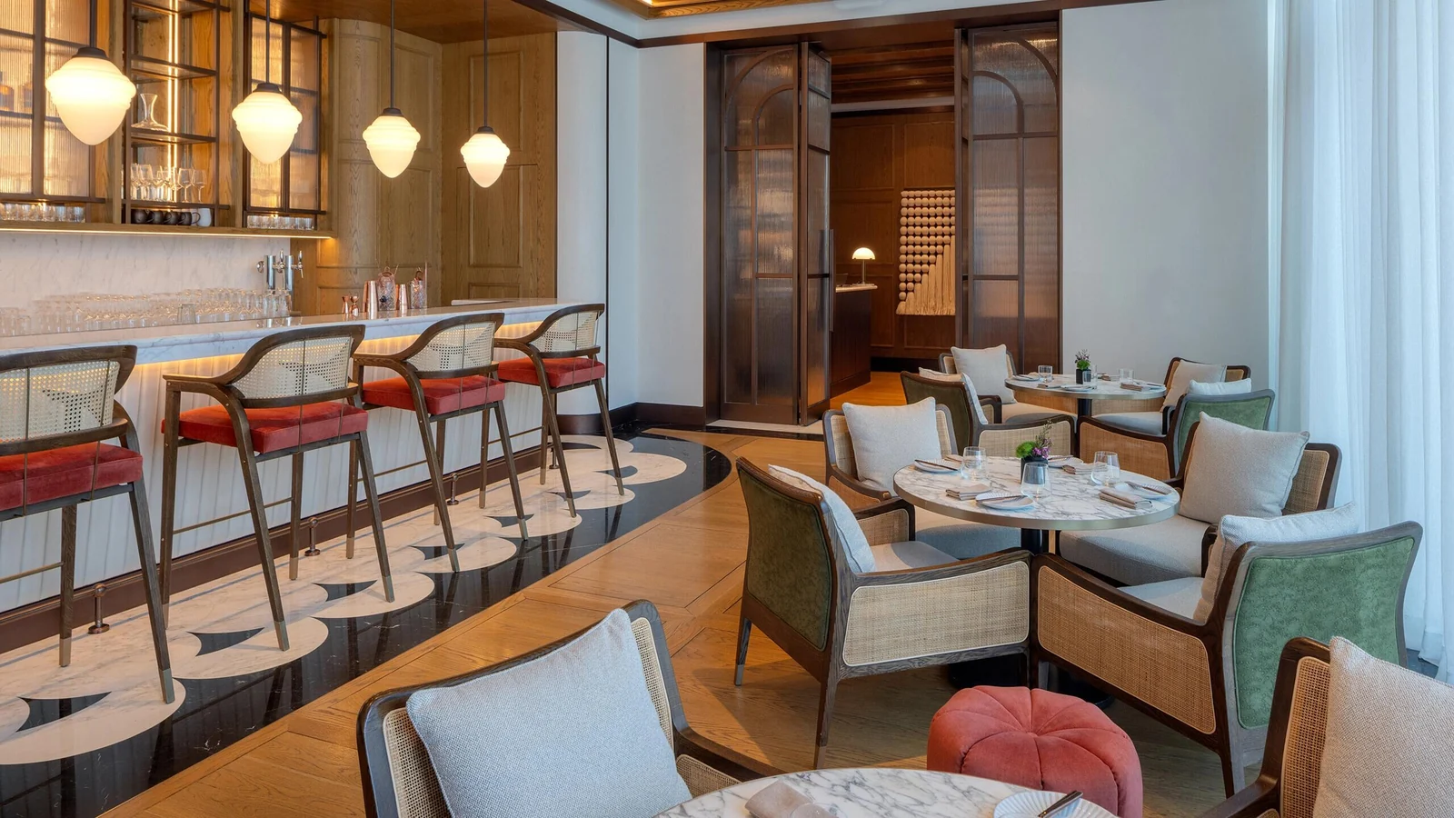 Bar counter seating beside round dining tables and loose armchairs