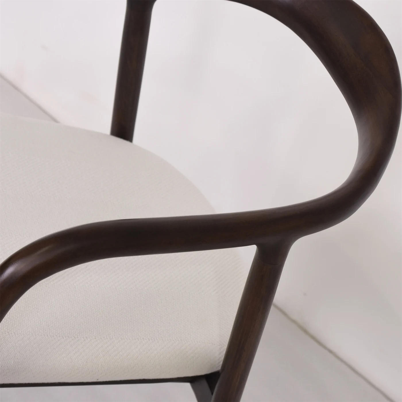 Dark curved chair frame beside light upholstered seating