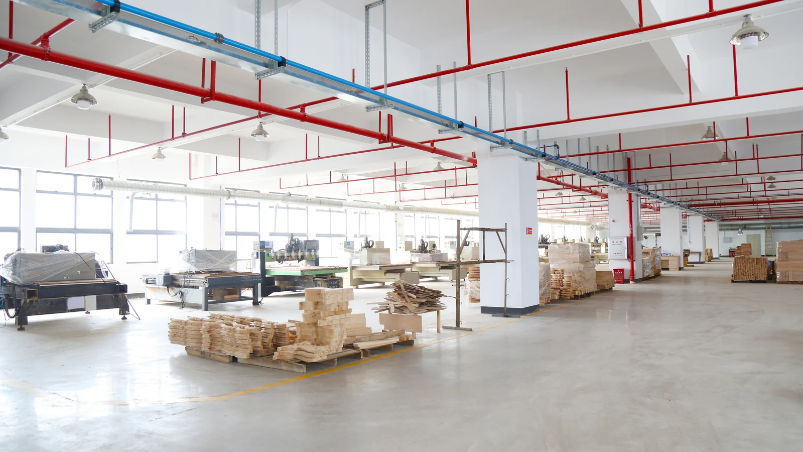 Furniture production workshop with automated machinery and stacked wood components