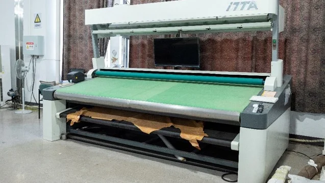 Fabric inspection machine with textile material across the inspection table