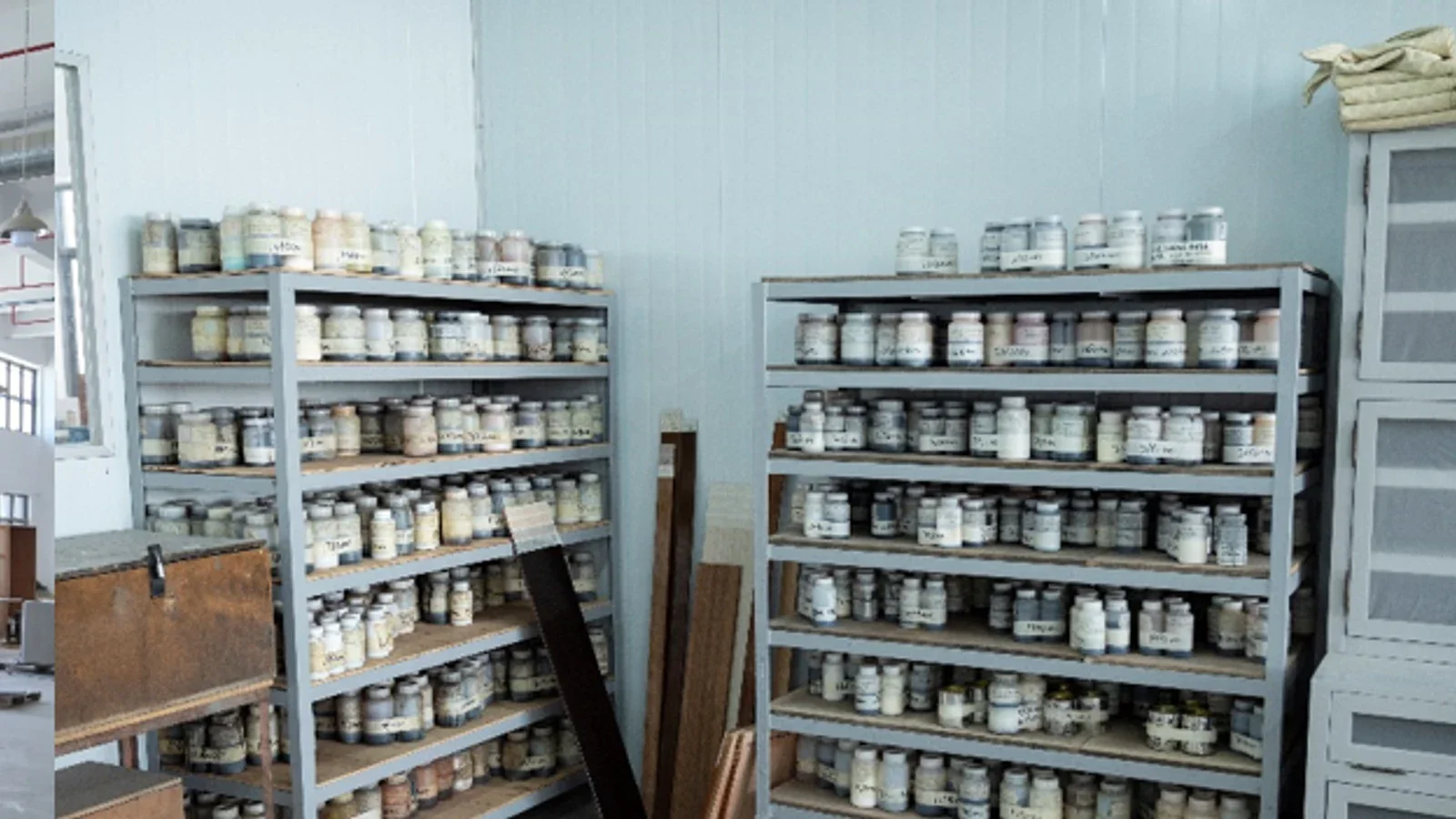 Labeled finish containers and sample boards on storage shelves