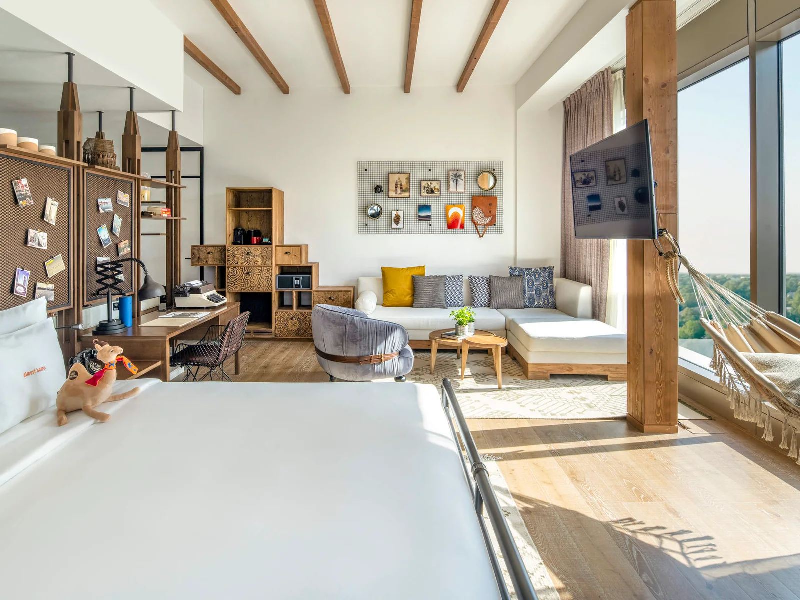 Hospitality room with bed, desk, storage, sofa, tables and television