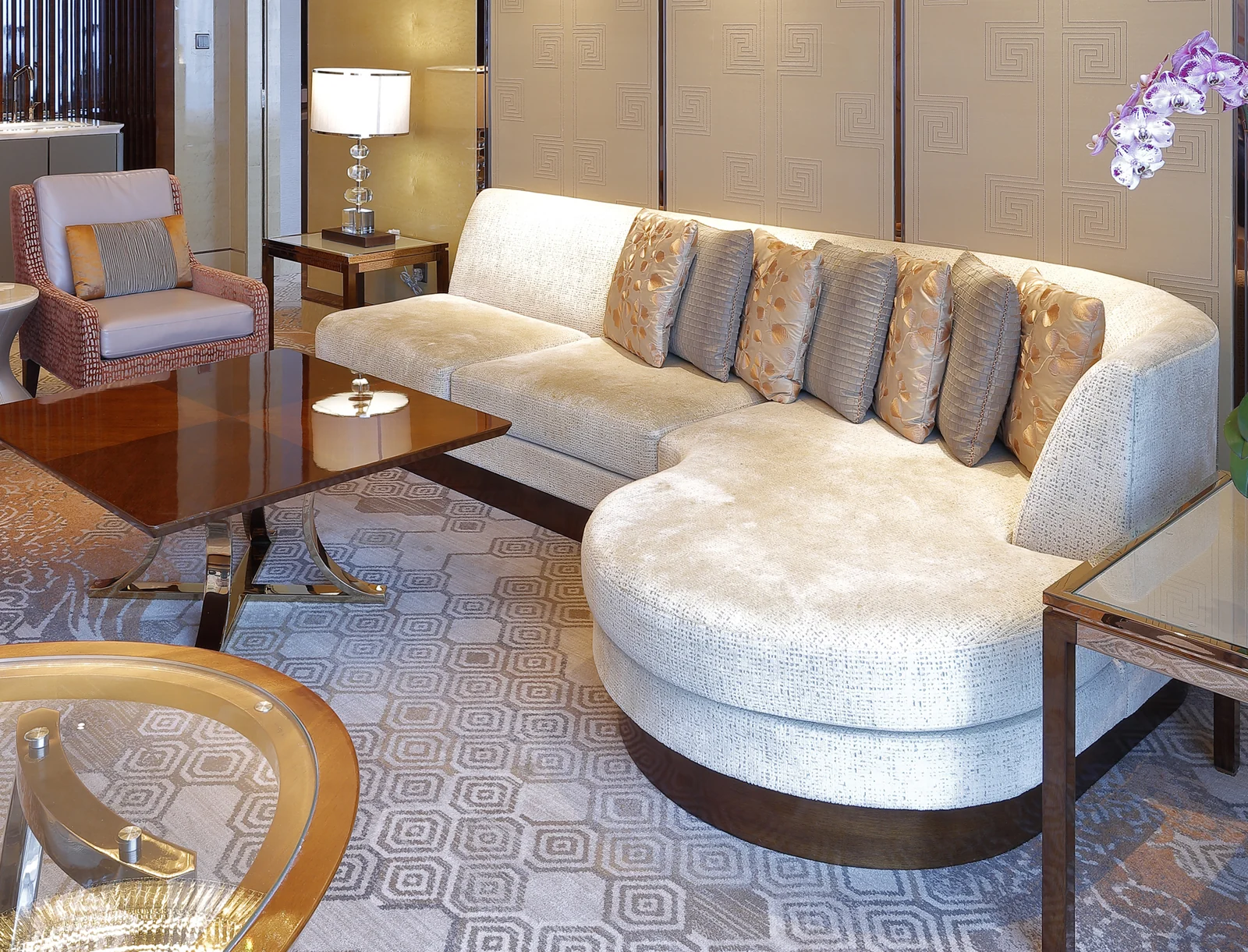 Hotel lobby conversation cluster with curved sofa, lounge chairs and coffee table
