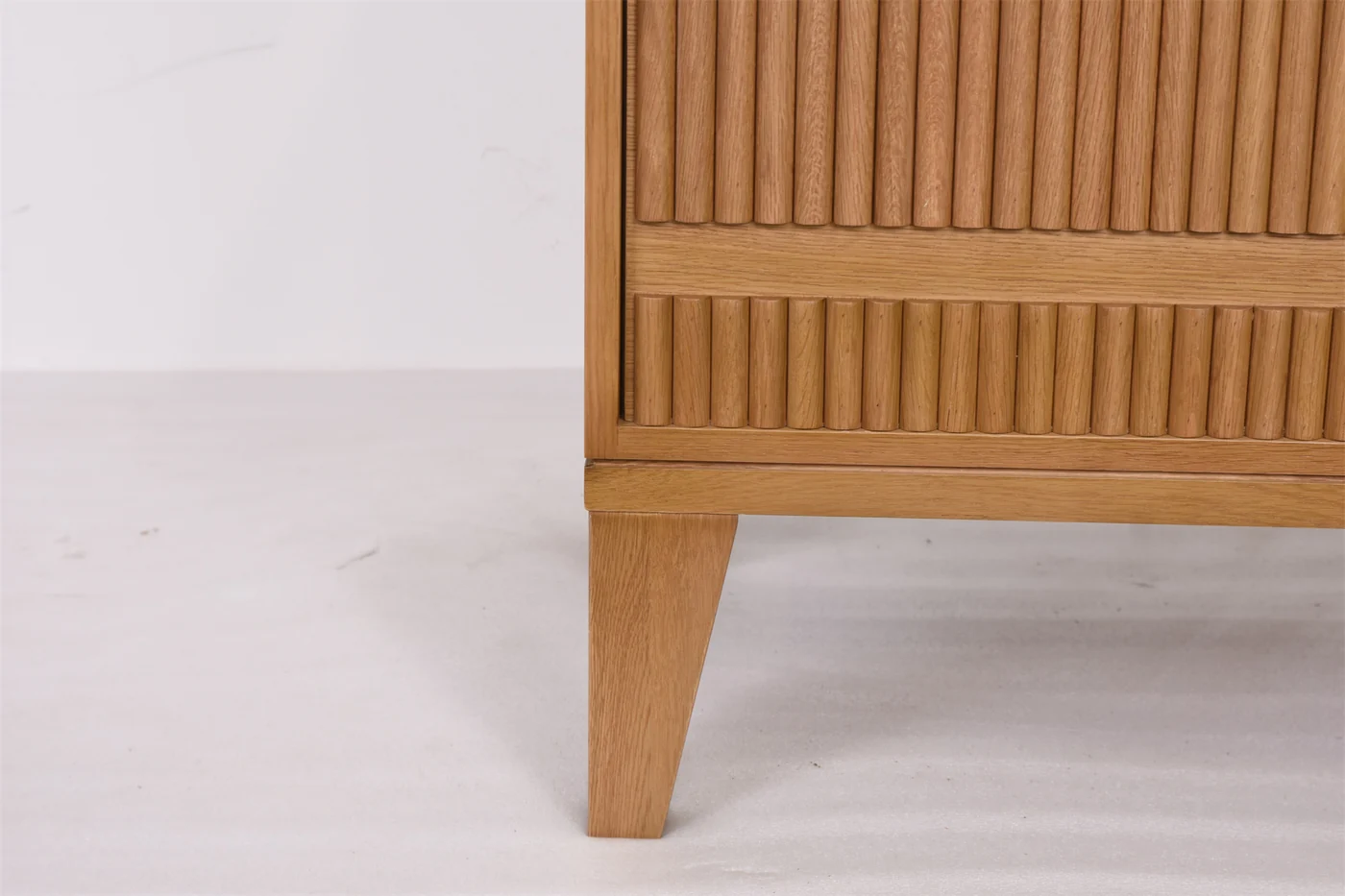Wood-toned nightstand detail with leg, lower rail and floor clearance