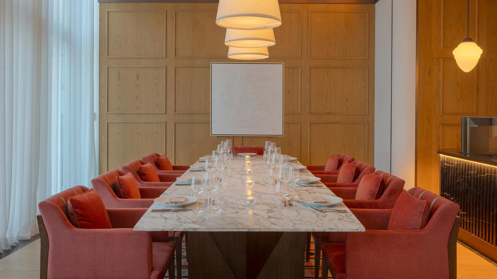 Long private dining table with upholstered armchairs on both sides and ends