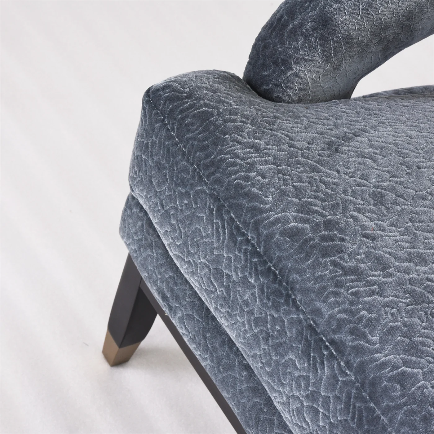 Blue upholstered lounge chair detail showing seams, arm and seat edge