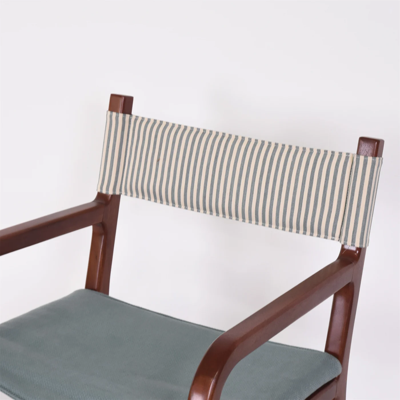 Dining chair detail with a wood-toned frame, striped wrapped back and upholstered seat