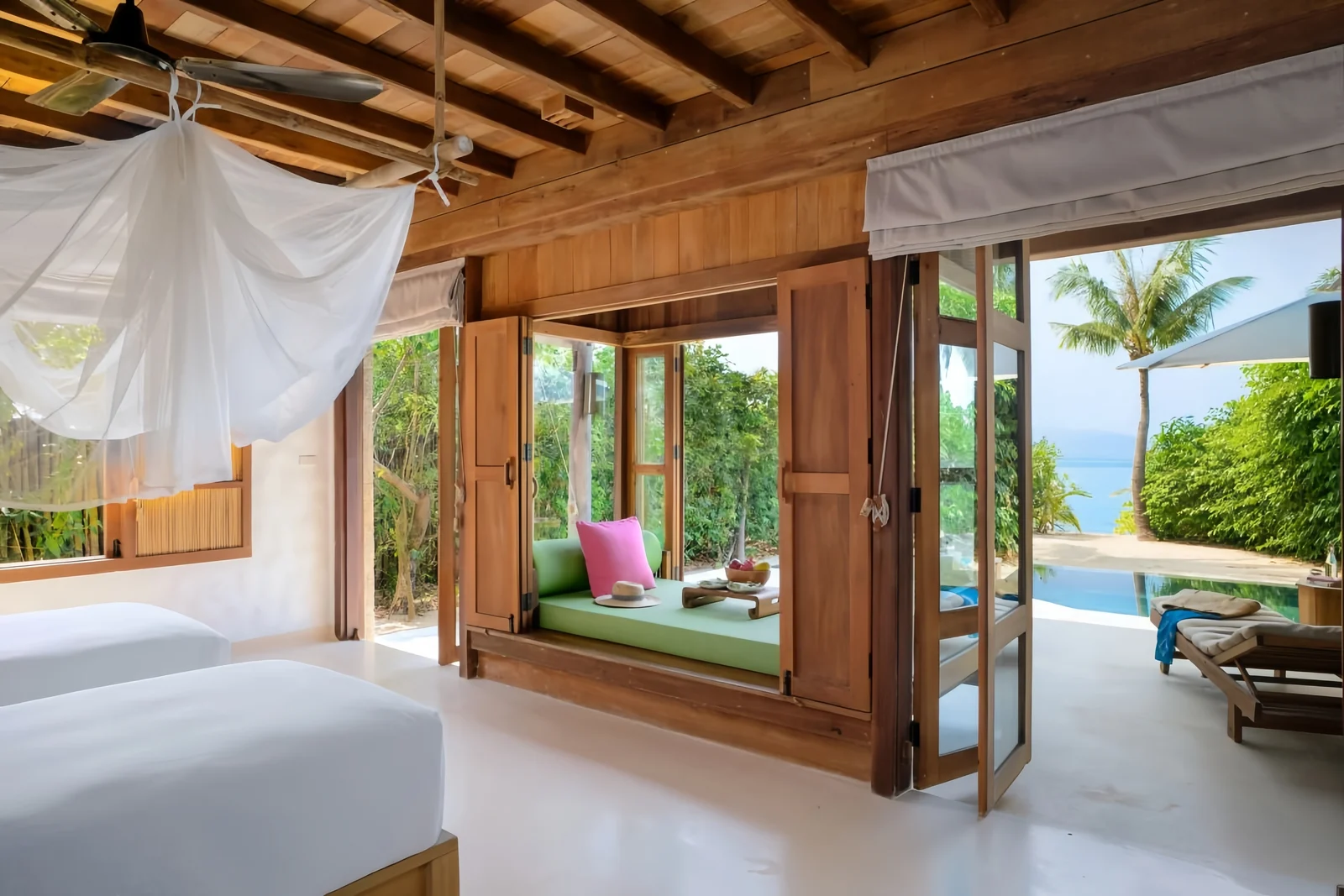 Hotel guestroom opening through doors to a pool terrace and outdoor lounger