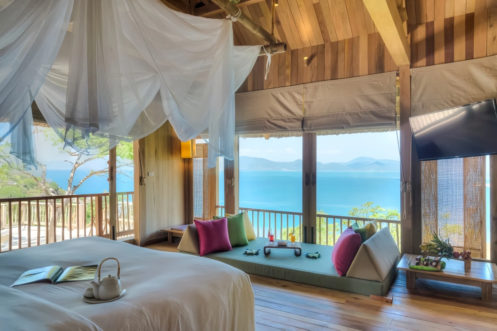 Open hotel room with built-in seating, loose cushions and exterior openings