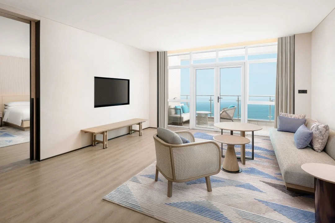 Hotel living area opening through doors to a furnished balcony