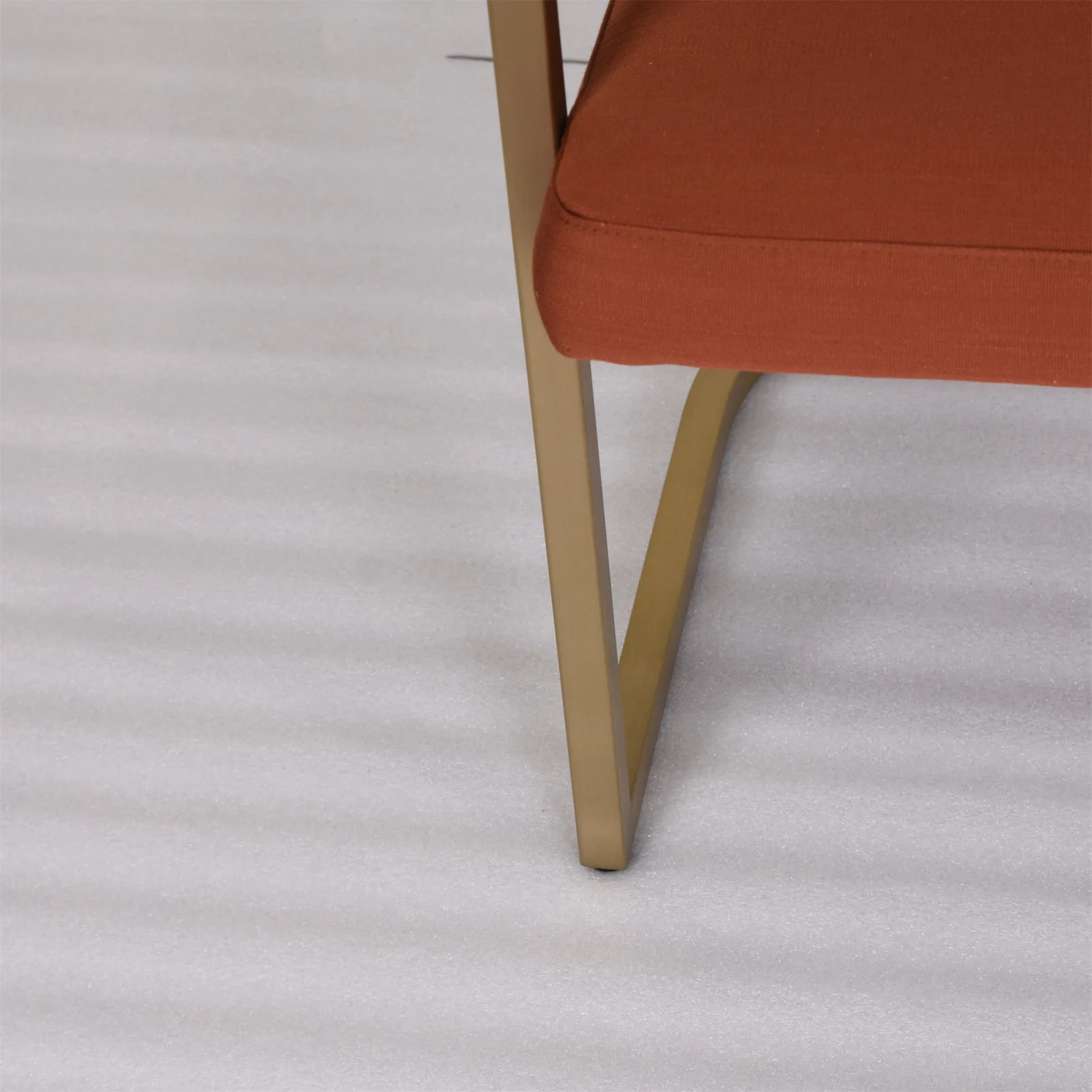 Bronze-colored chair rail and leg beside an upholstered seat edge