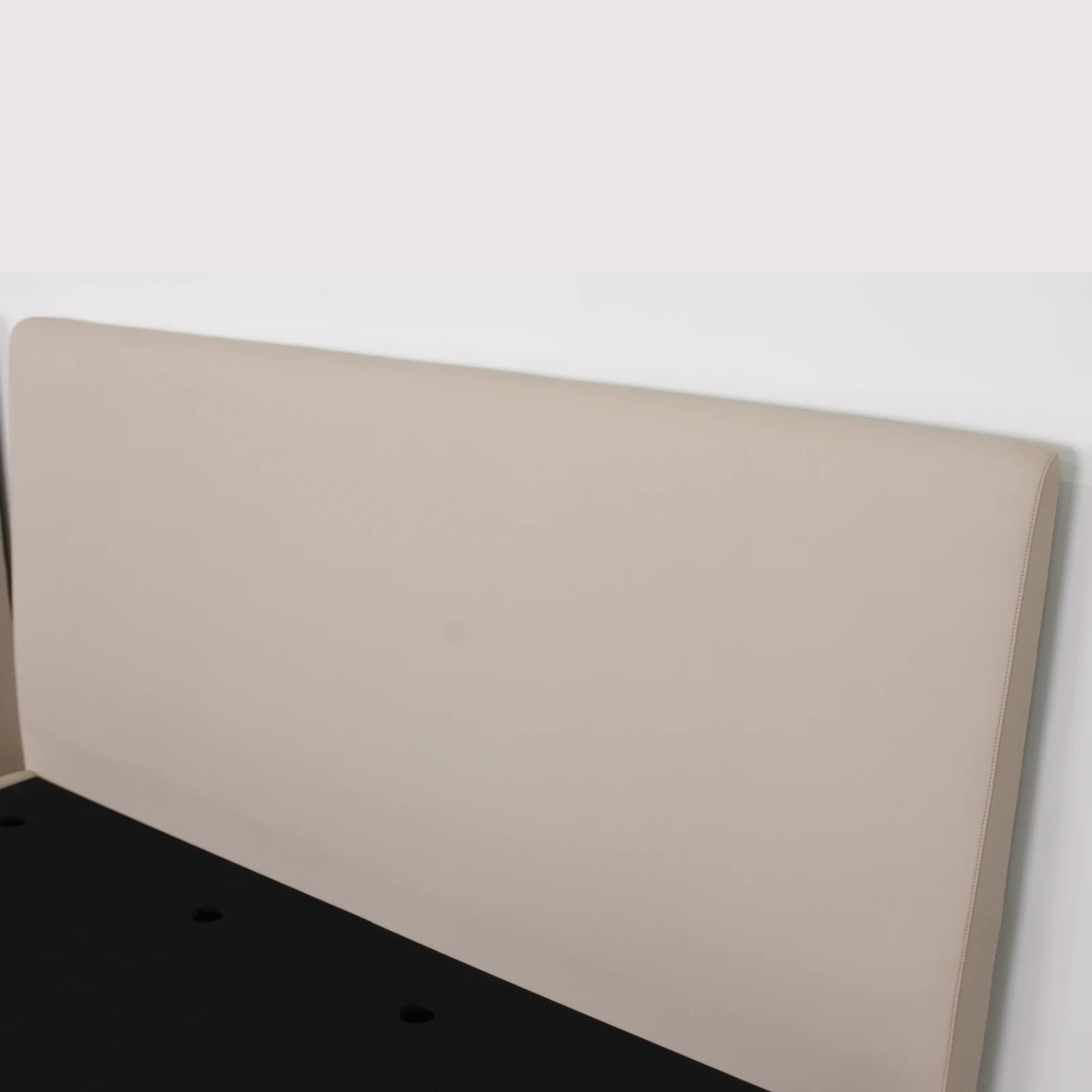 Close view of a plain light headboard with stitched side edge