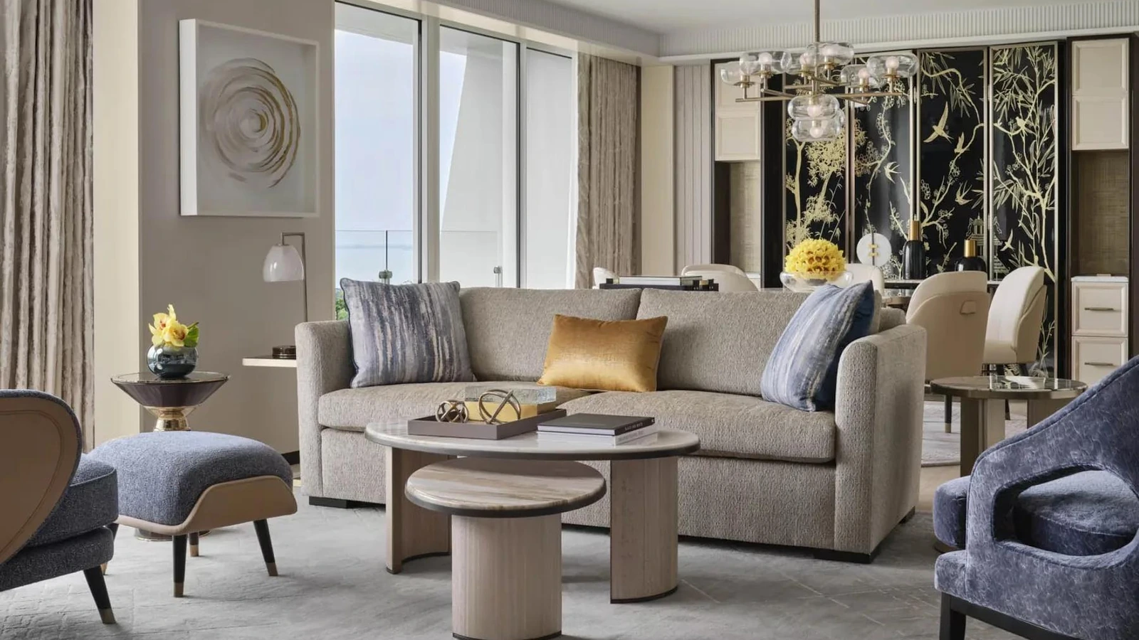 A sofa and individual lounge chairs arranged around nested coffee tables.