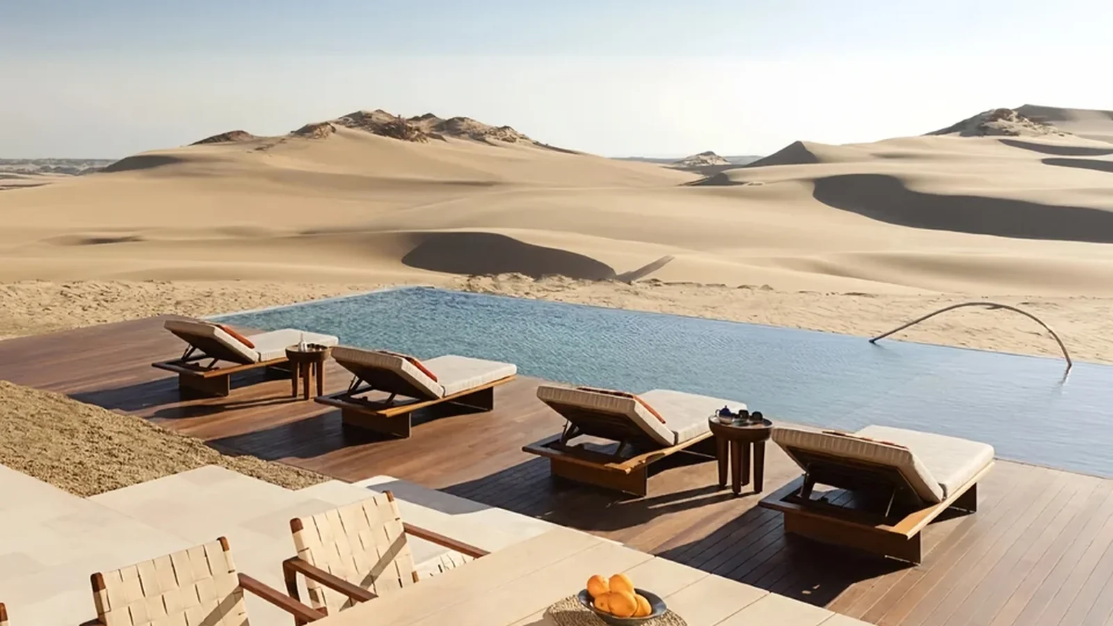 Acacia-style timber loungers beside an exposed hotel pool