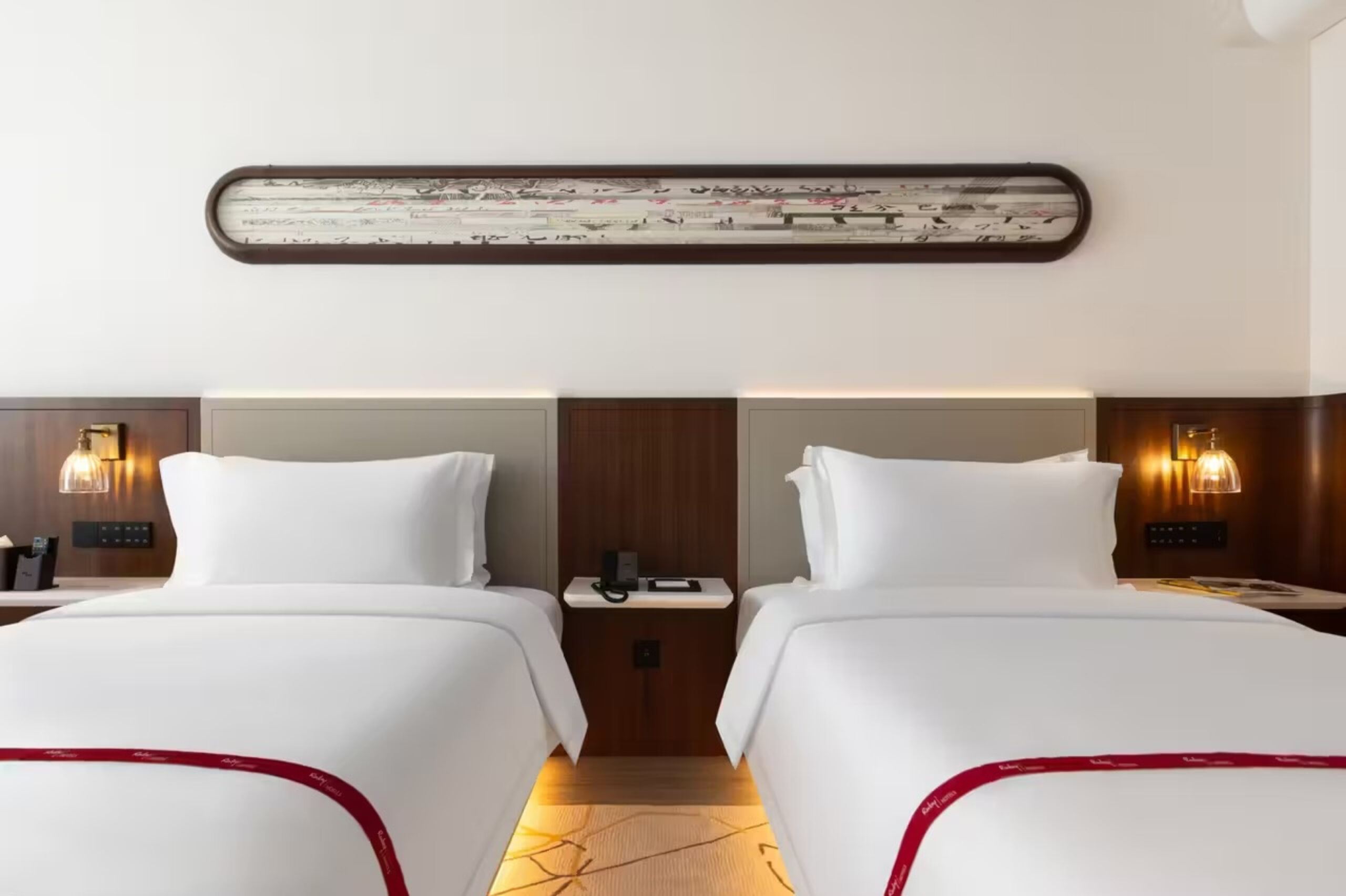 Hotel twin room combining loose beds with an integrated headboard wall
